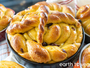 a large round paska loaf sits surrounded by smaller paskas on a gingham towel.