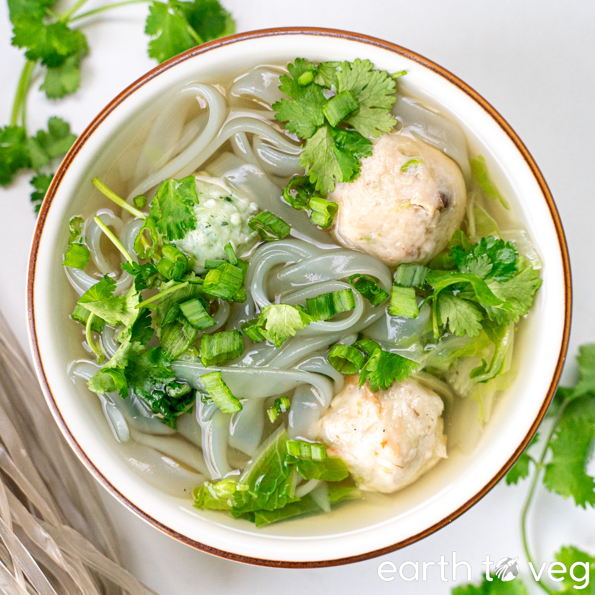 A bowl of vegan fish ball soup on a white marble countertop.